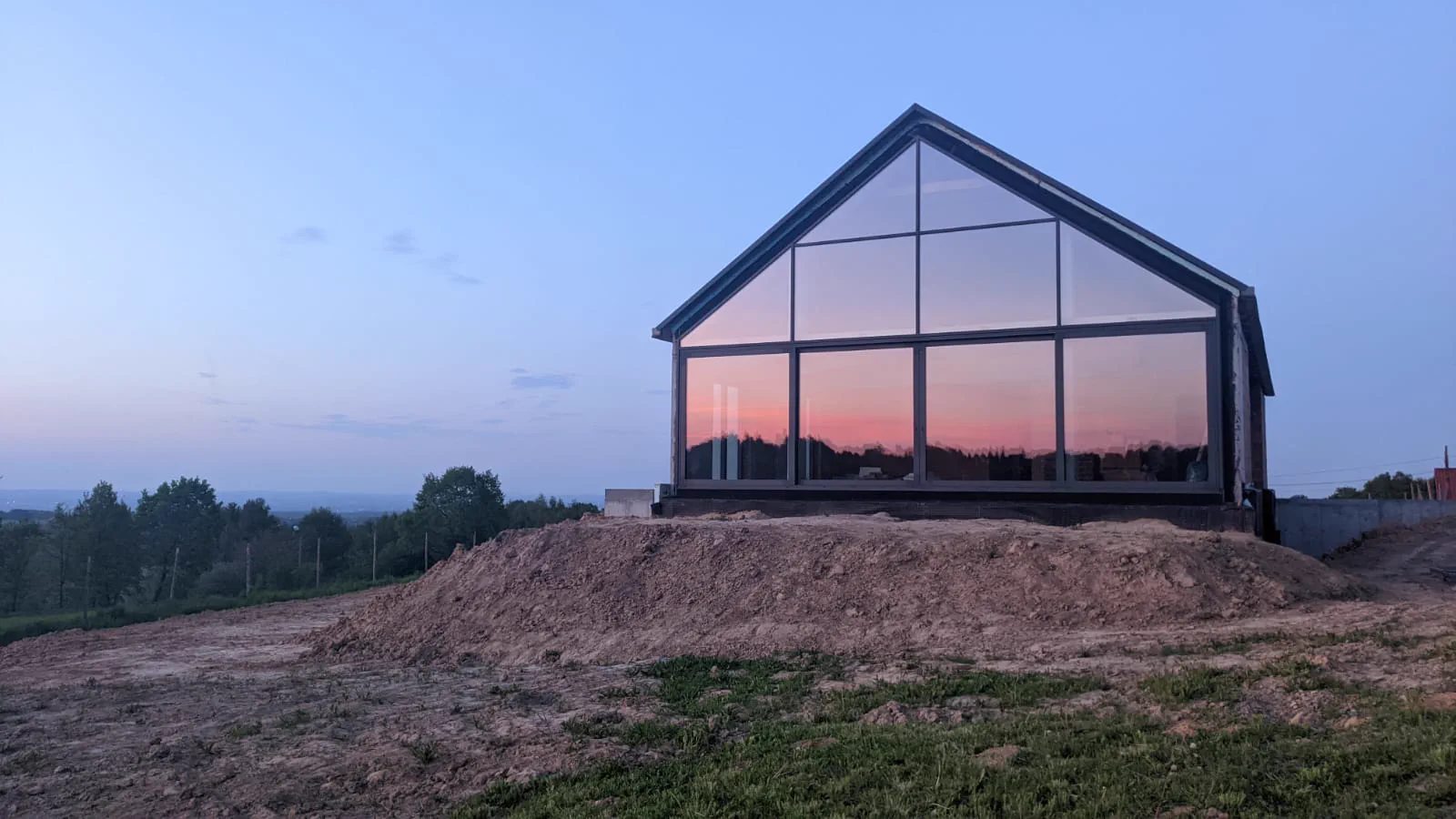 Großformatige Aluminium-Glas-Fassade eines modernen Hauses bei Sonnenuntergang